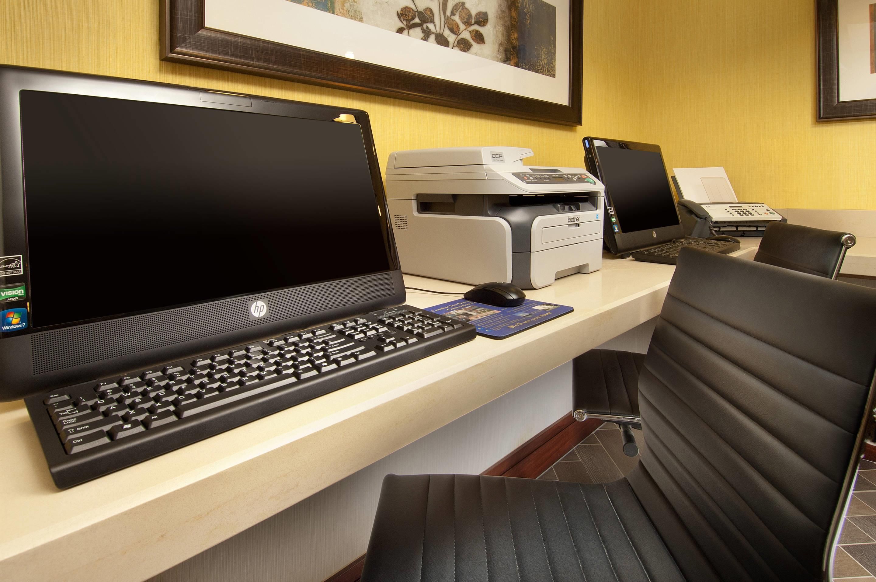 A hotel reception desk with a laptop, desktop computer, printer, and telephone.
