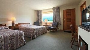 A hotel room with two beds, a chair, a desk, and a window with curtains. - Ladd Brook Inn (Pownal)