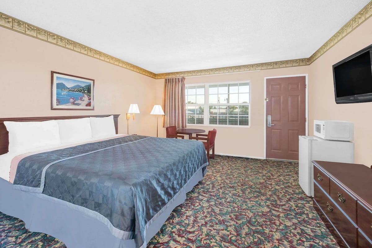 Une chambre d’hôtel avec un lit, un bureau, une télévision et une fenêtre.