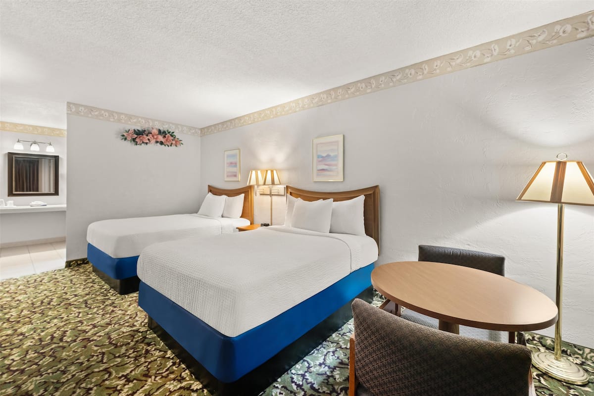 Une chambre d’hôtel avec deux lits, une table ronde et une chaise.