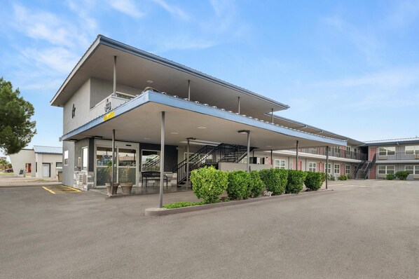 A modern building with a covered entrance, a staircase, and a parking lot.