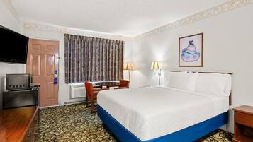 Una habitación de hotel con una cama, un escritorio, un televisor y una ventana con cortinas.