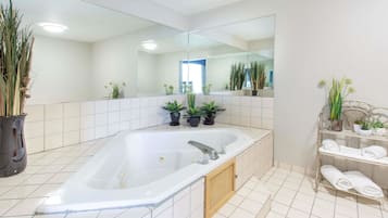 Un baño moderno con una bañera grande, un espejo y plantas en macetas.