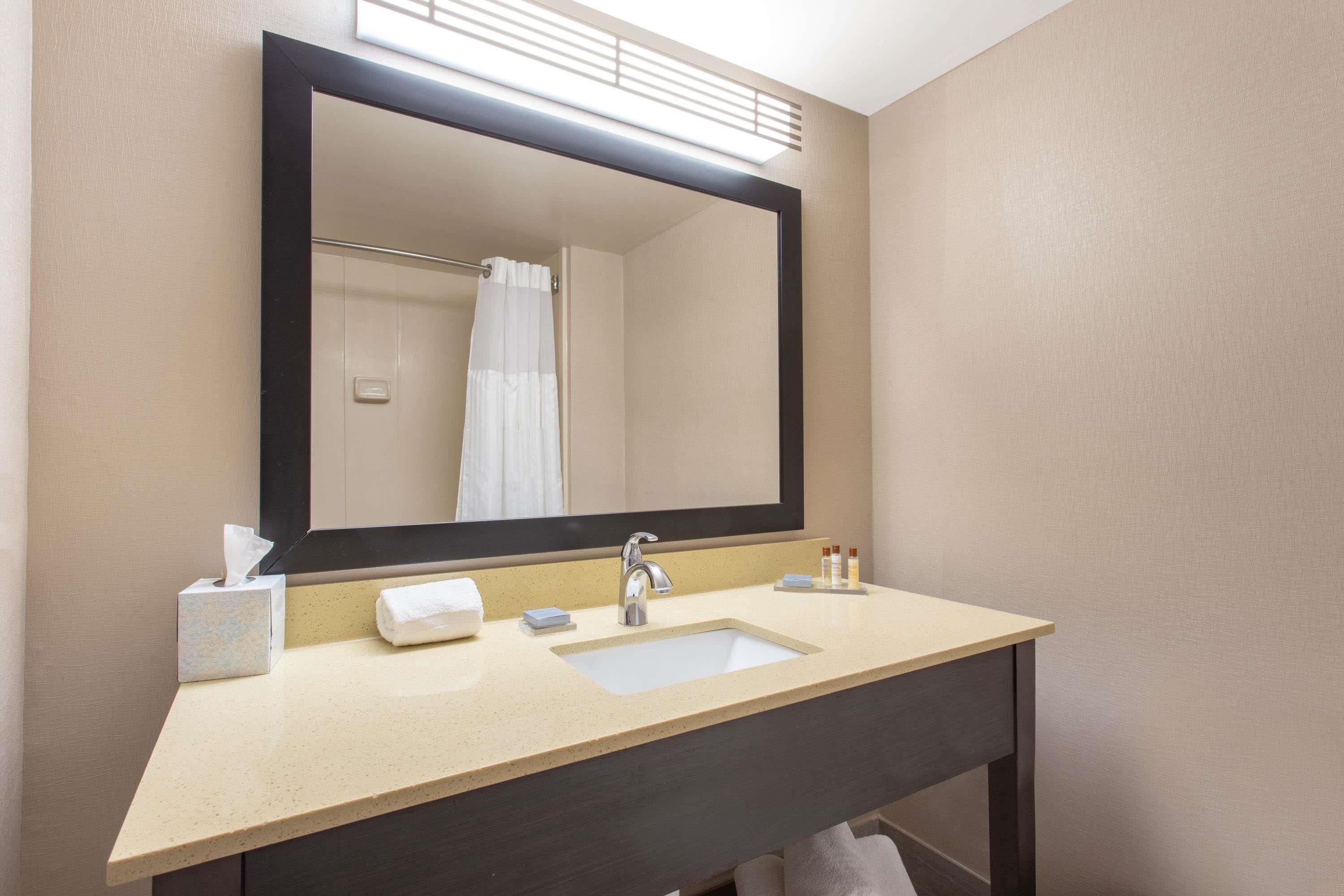 Une salle de bain avec un grand miroir, un lavabo et un porte-serviettes.