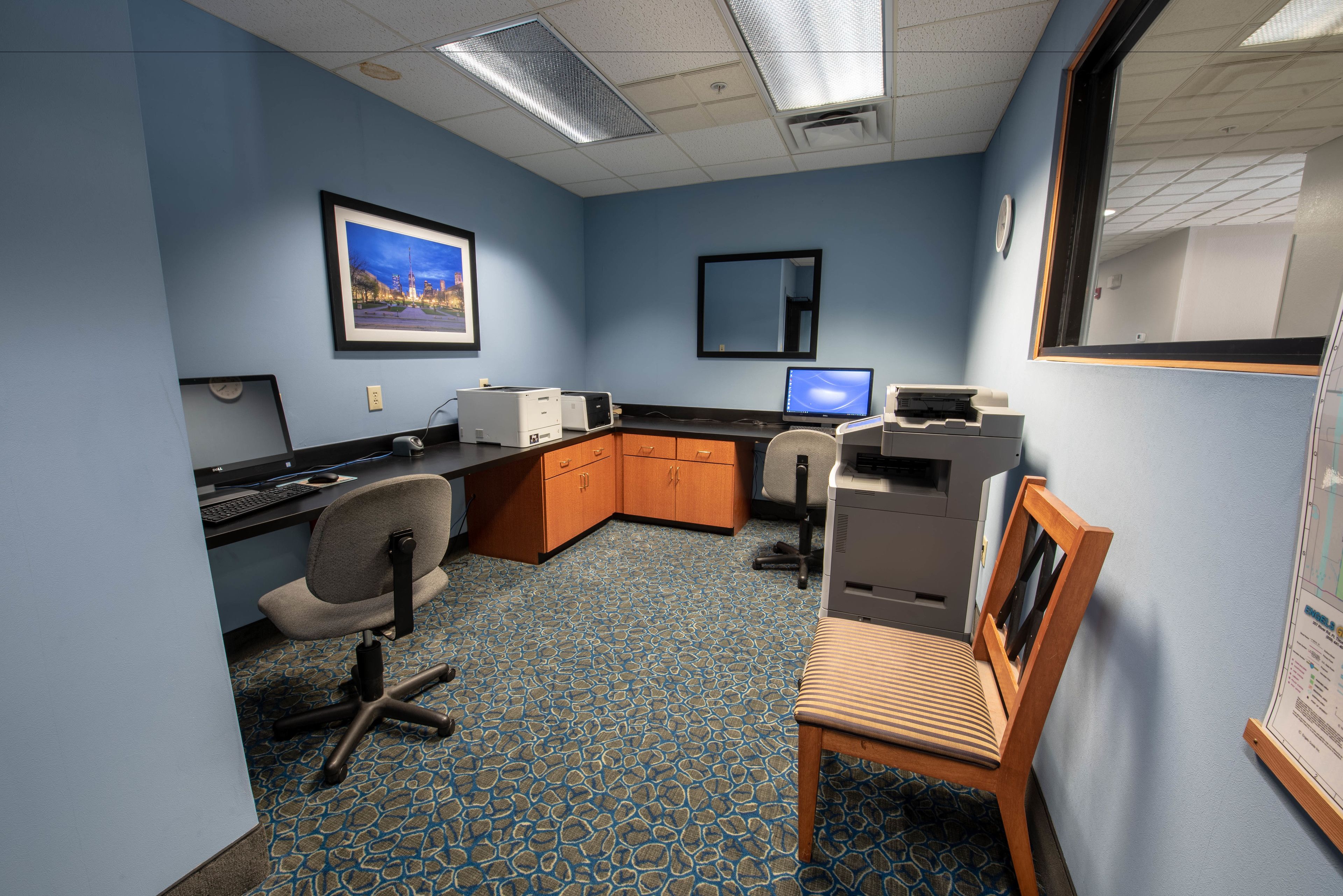 An office with a blue carpet, a desk with a computer, a chair, and a printer.