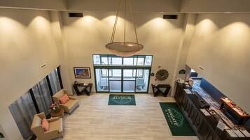 A spacious lobby with a reception desk, seating area, and large windows.