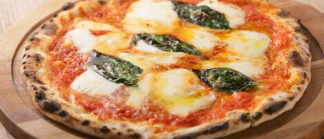 A pizza with cheese and spinach on a wooden board.