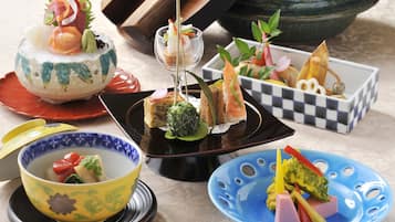 Diverse gerechten op verschillende borden, waaronder sushi, sashimi en andere hapjes.