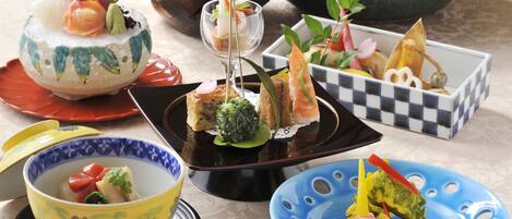 A variety of dishes on different plates, including sushi, sashimi, and other appetizers.