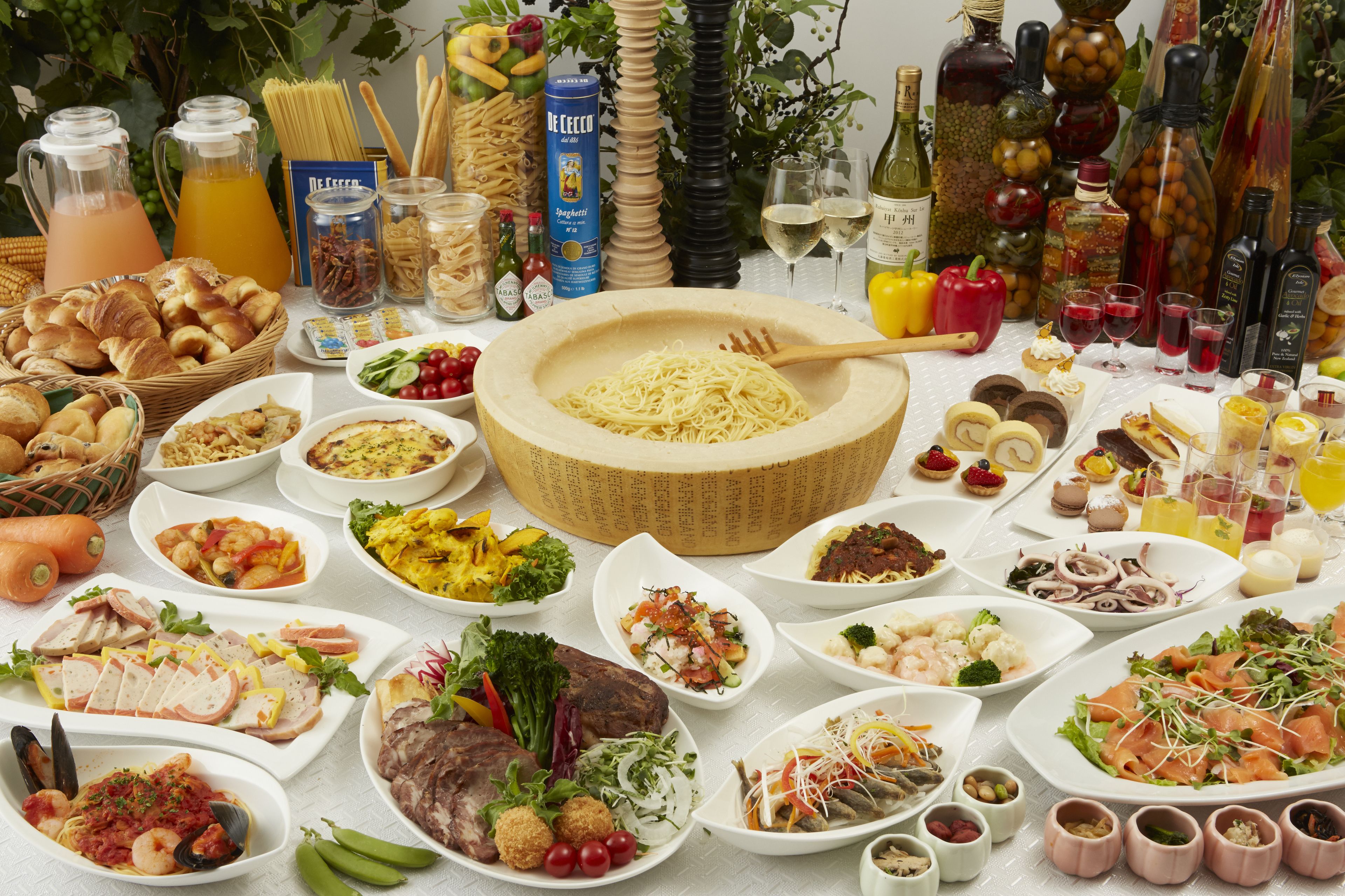 Una mesa llena de diversos platos, como pasta, ensaladas y carnes, rodeada de salsas y bebidas.