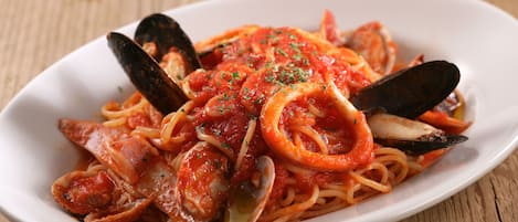 Un plato de espagueti con almejas y camarones, adornado con hierbas.