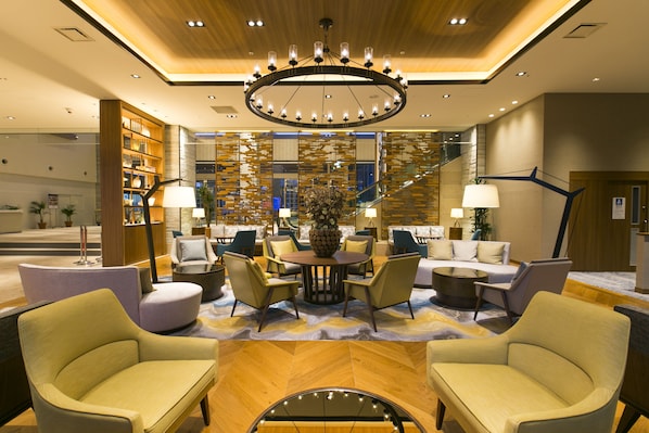 A modern lobby with a central round table, seating area, and a staircase. - Highland Resort Hotel & Spa (Fujiyoshida)