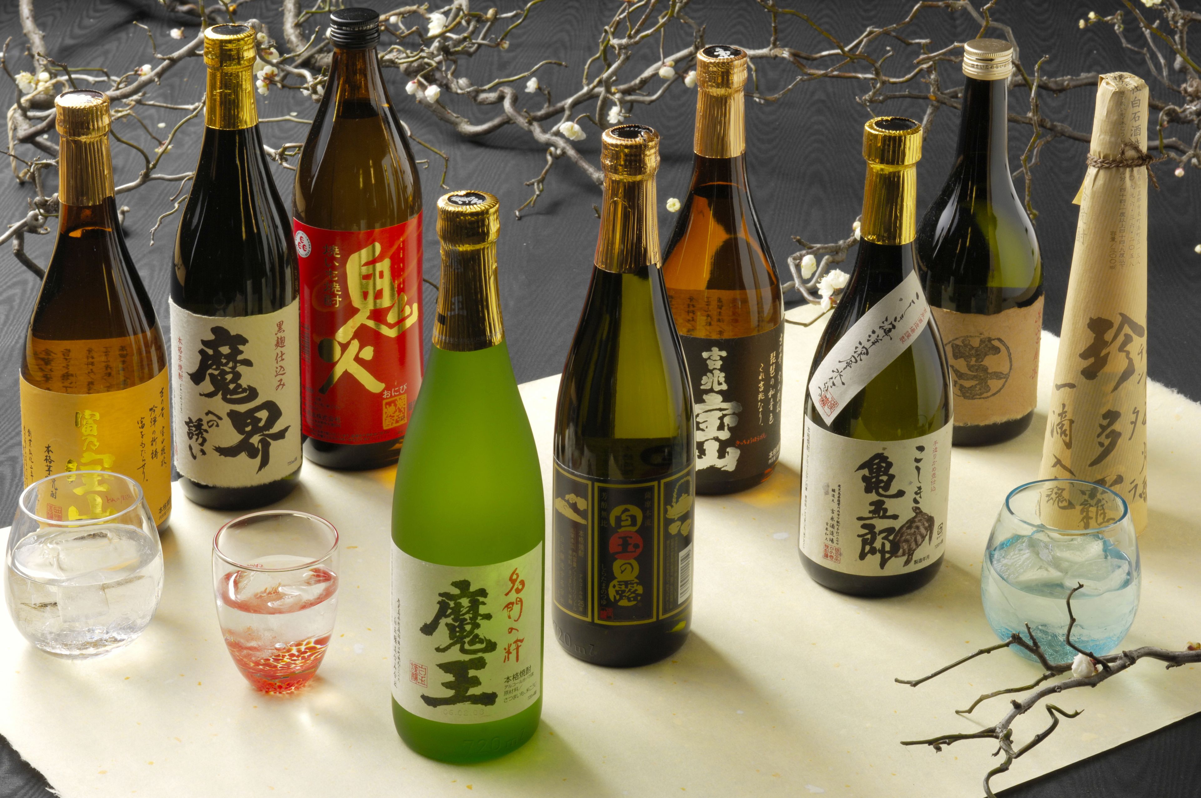 A variety of bottles and glasses on a table, likely containing different types of beverages.