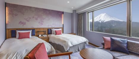 Une chambre d’hôtel avec deux lits, un canapé, une petite table et une grande fenêtre donnant sur une vue sur la montagne.