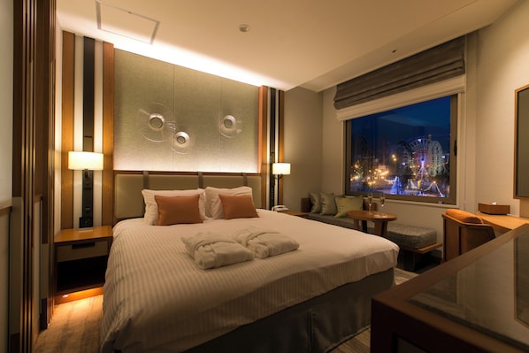 A hotel room with a large bed, a TV, a window with a city view, and a desk with a lamp. - Highland Resort Hotel & Spa (Fujiyoshida)