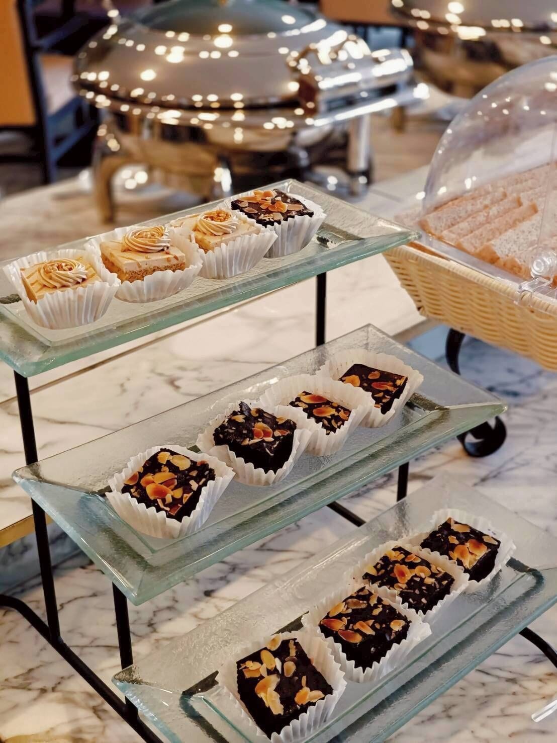 A display of assorted desserts on glass stands in a dining area.