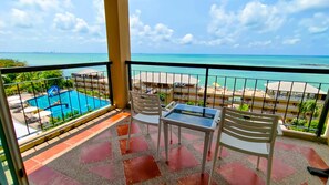 Un balcón con vista a la piscina, mobiliario exterior y una vista despejada del océano.