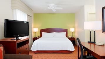 A hotel room with a bed, a TV, a desk, and a chair.
