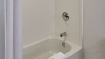 Un baño moderno con una bañera independiente, cabezal de ducha y un perchero para toallas.