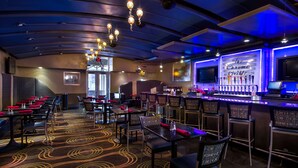 A bar area with a sign reading "The Chrome Grille," tables, chairs, and a patterned carpet. - Hilton Garden Inn Detroit Downtown (Detroit)