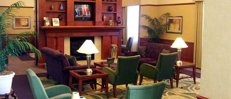 Un hall de hotel con chimenea, asientos cómodos y un televisor.