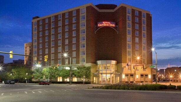 A Hilton Garden Inn hotel with a prominent sign, multiple floors, and a corner entrance. - Hilton Garden Inn Detroit Downtown (Detroit)