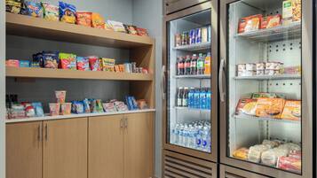 A kitchenette with shelves stocked with snacks, beverages, and packaged food items.