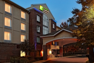 Um hotel Holiday Inn Express & Suites com fachada de tijolos, grandes janelas e área de entrada coberta.