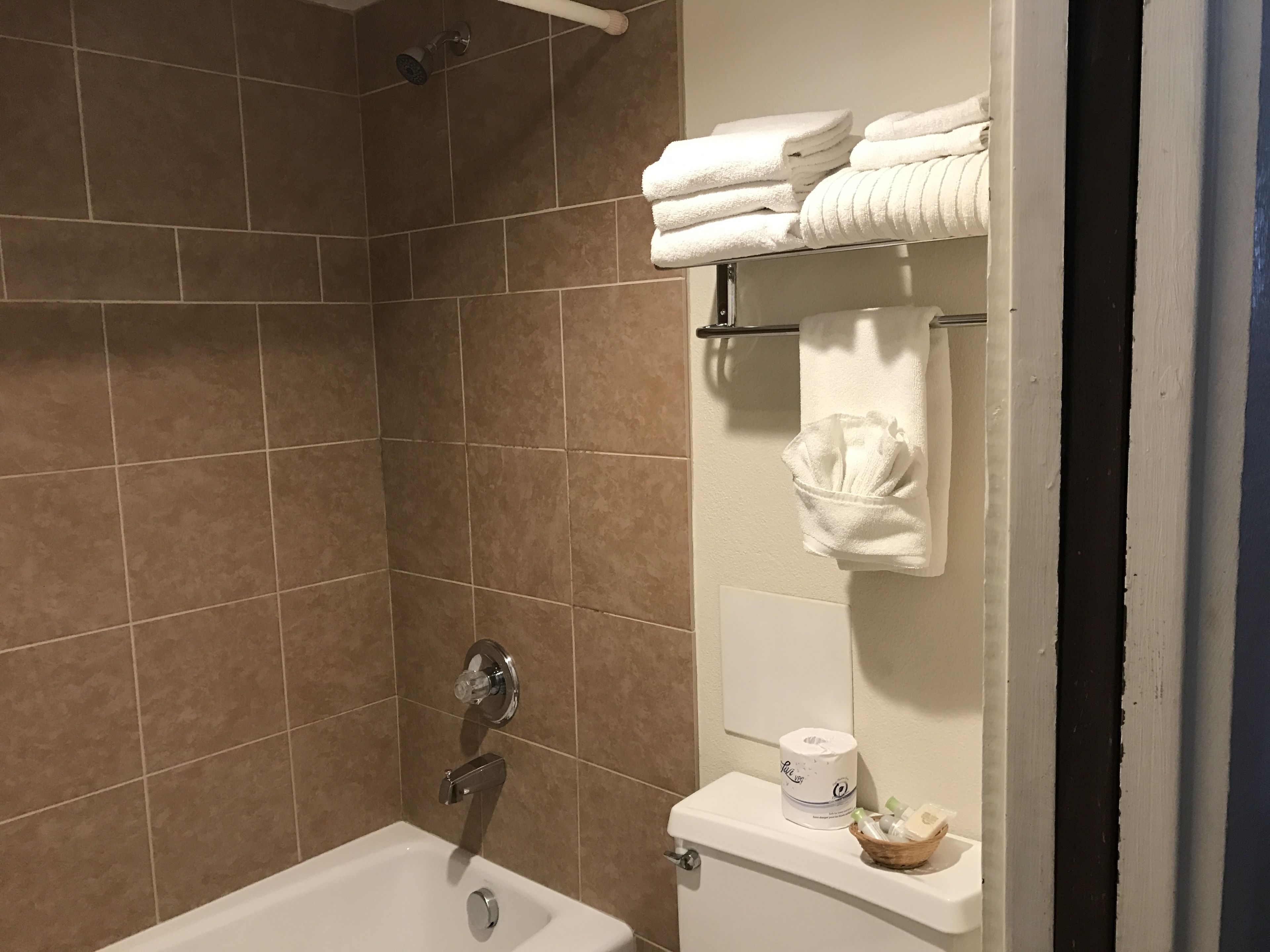 Ein Badezimmer mit einer Badewanne, einer Toilette und einem Handtuchhalter mit gefalteten Handtüchern.