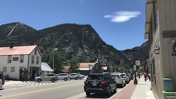 A street view with buildings, cars, and mountains in the background.