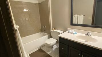 Un baño con bañera, inodoro, tocador con espejo y perchero.