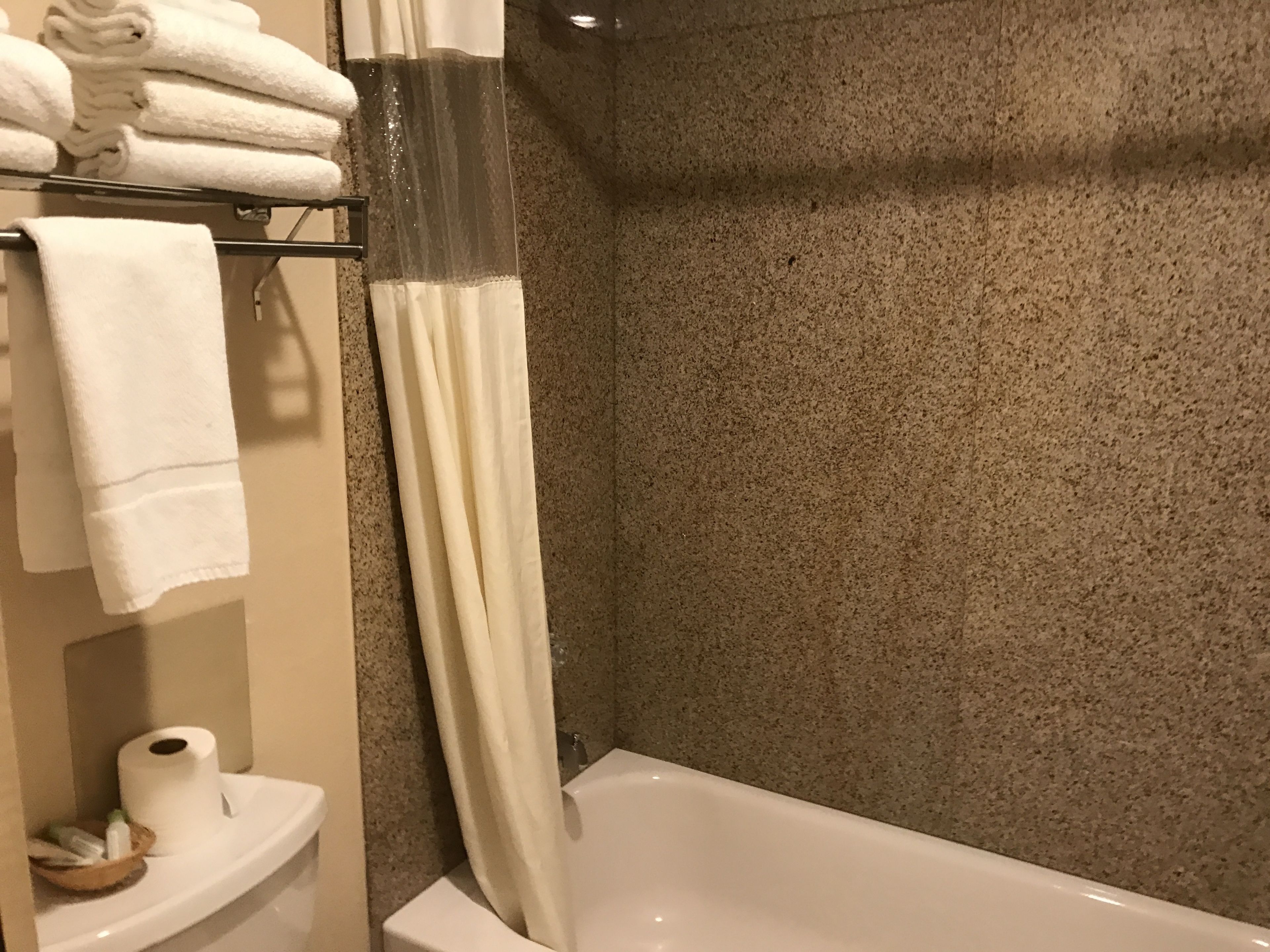 A bathroom with a bathtub, a shower curtain, and a towel rack with folded towels.