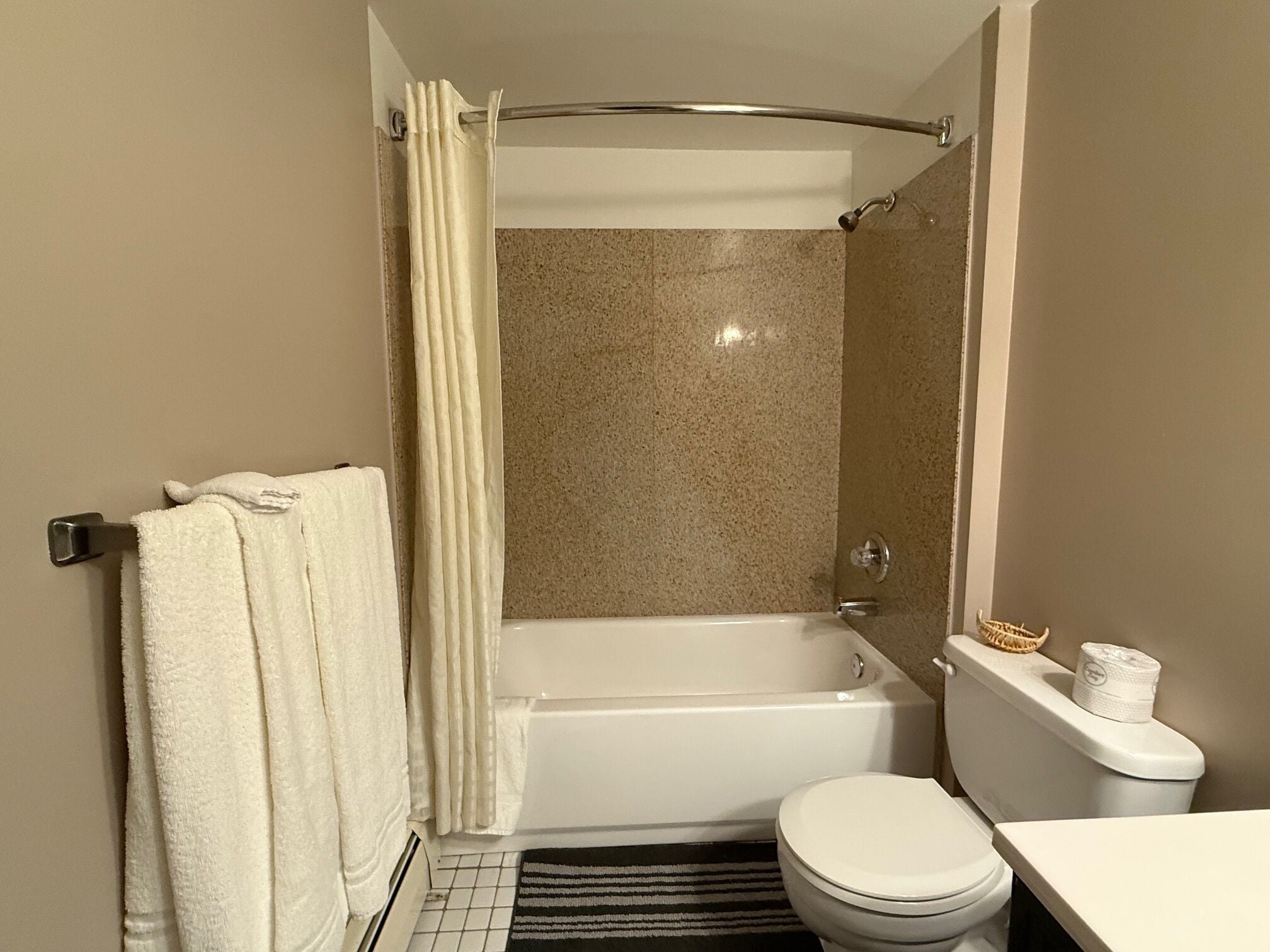 Un baño con bañera, inodoro y cortina de ducha.
