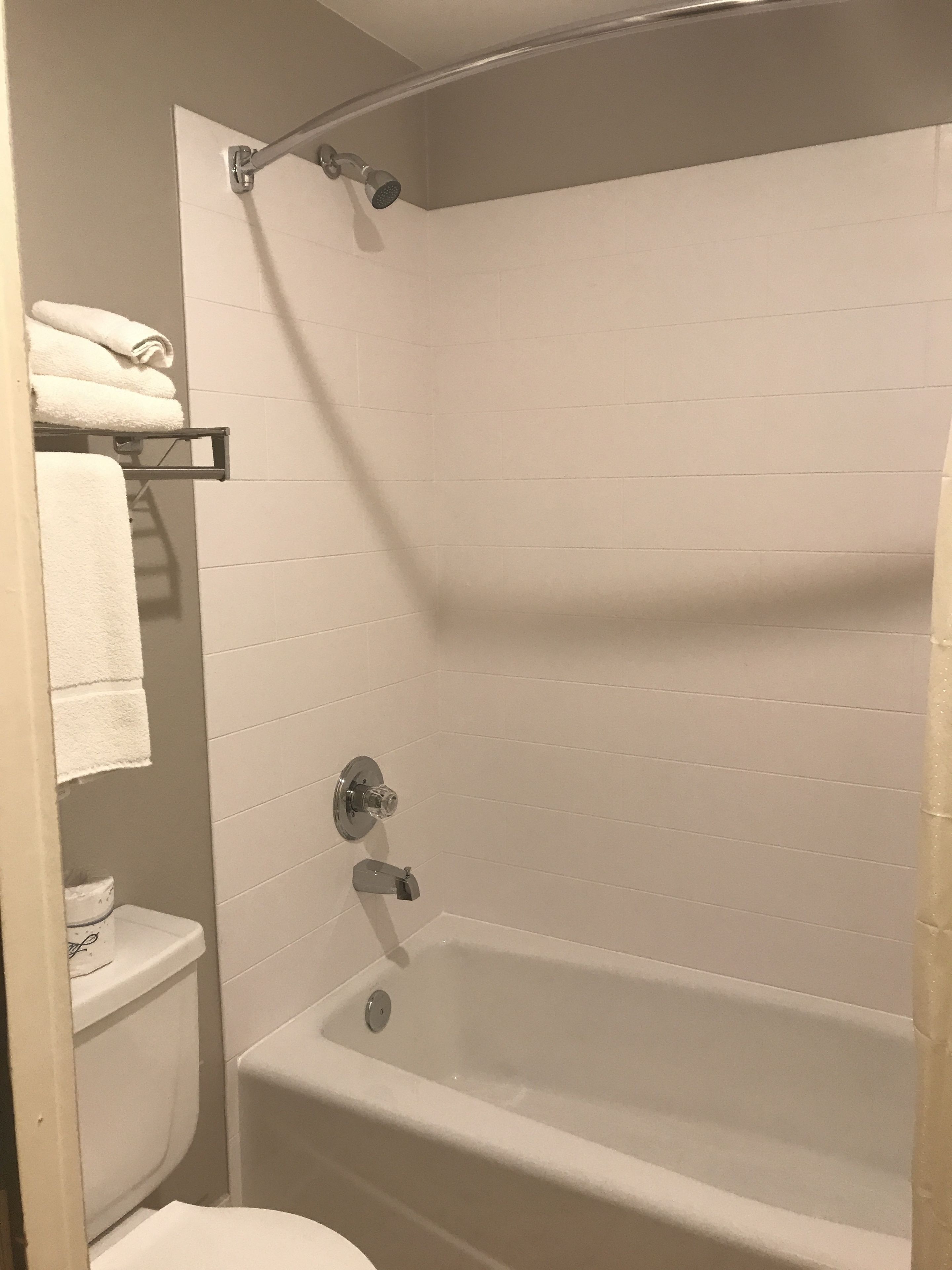 A bathroom with a bathtub, a toilet, and a towel rack.