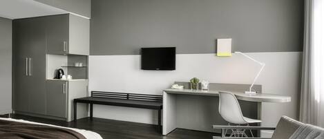 Habitación de hotel moderna con cama, escritorio, silla, televisión y ventana.