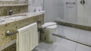 A modern bathroom with a granite countertop, a toilet, a shower area, and a glass-enclosed shower stall.