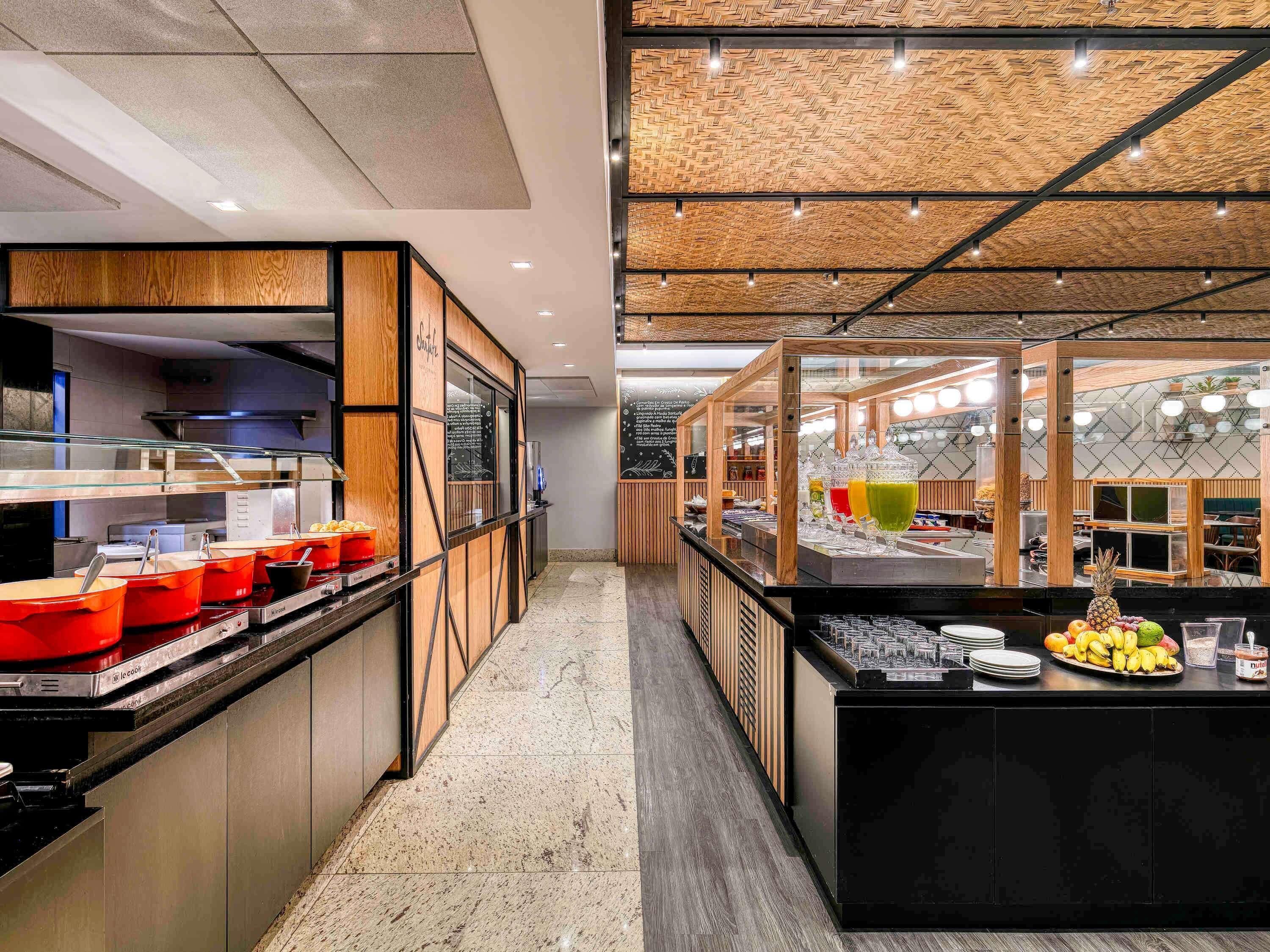 A modern kitchen area with a buffet setup, including a counter with food containers and a display of fruits.