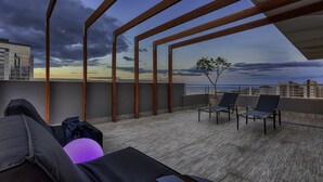 A rooftop terrace with a view of the city skyline, a seating area with chairs, and a small plant. - Caesar Business Belo Horizonte Belvedere Managed by Mercure (Belo Horizonte)