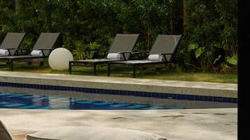 Un área de piscina con sillones de descanso y una terraza de madera.