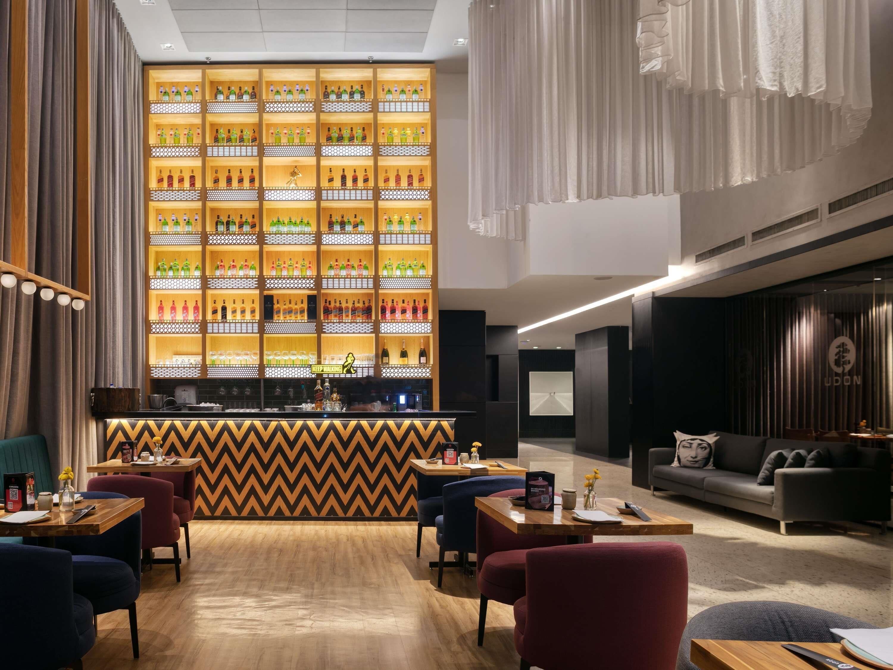 Un espace bar moderne, avec un assortiment de bouteilles et un mur orné d’un motif en chevrons.