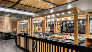 Un mostrador de comida con estructura de madera y vitrina de vidrio, rodeado de asientos y un techo con diseño.