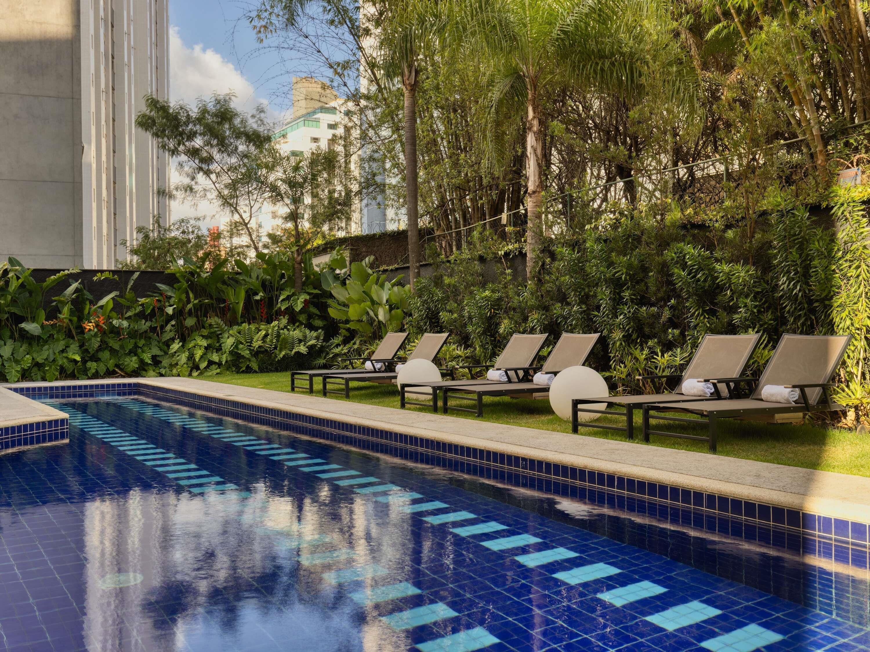 Una piscina al aire libre, sillones reclinables de piscina