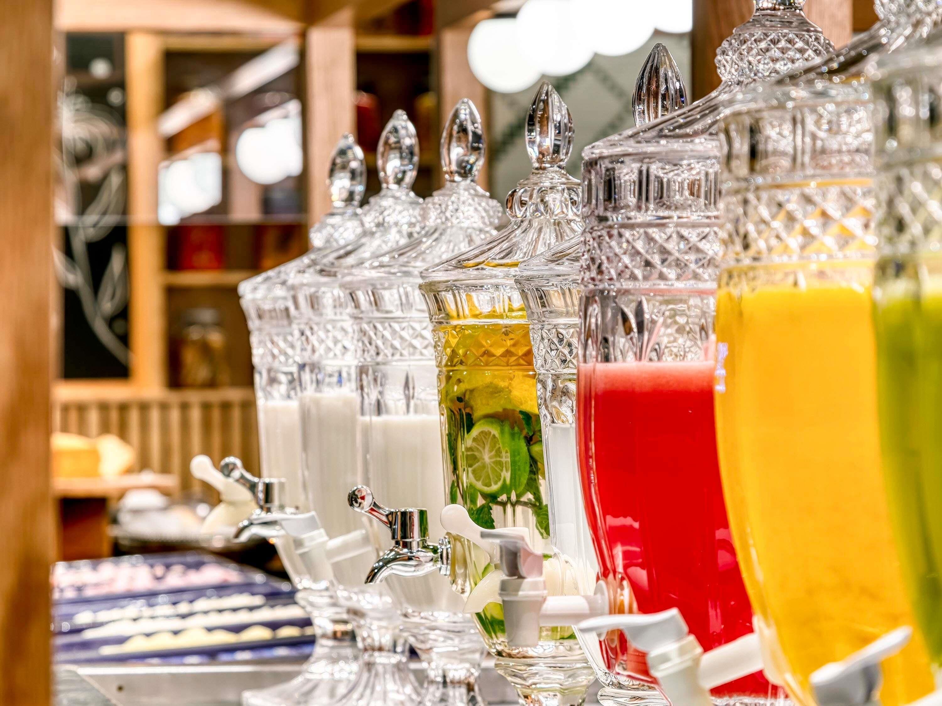 A row of glass dispensers with various colored liquids, each with a pump.