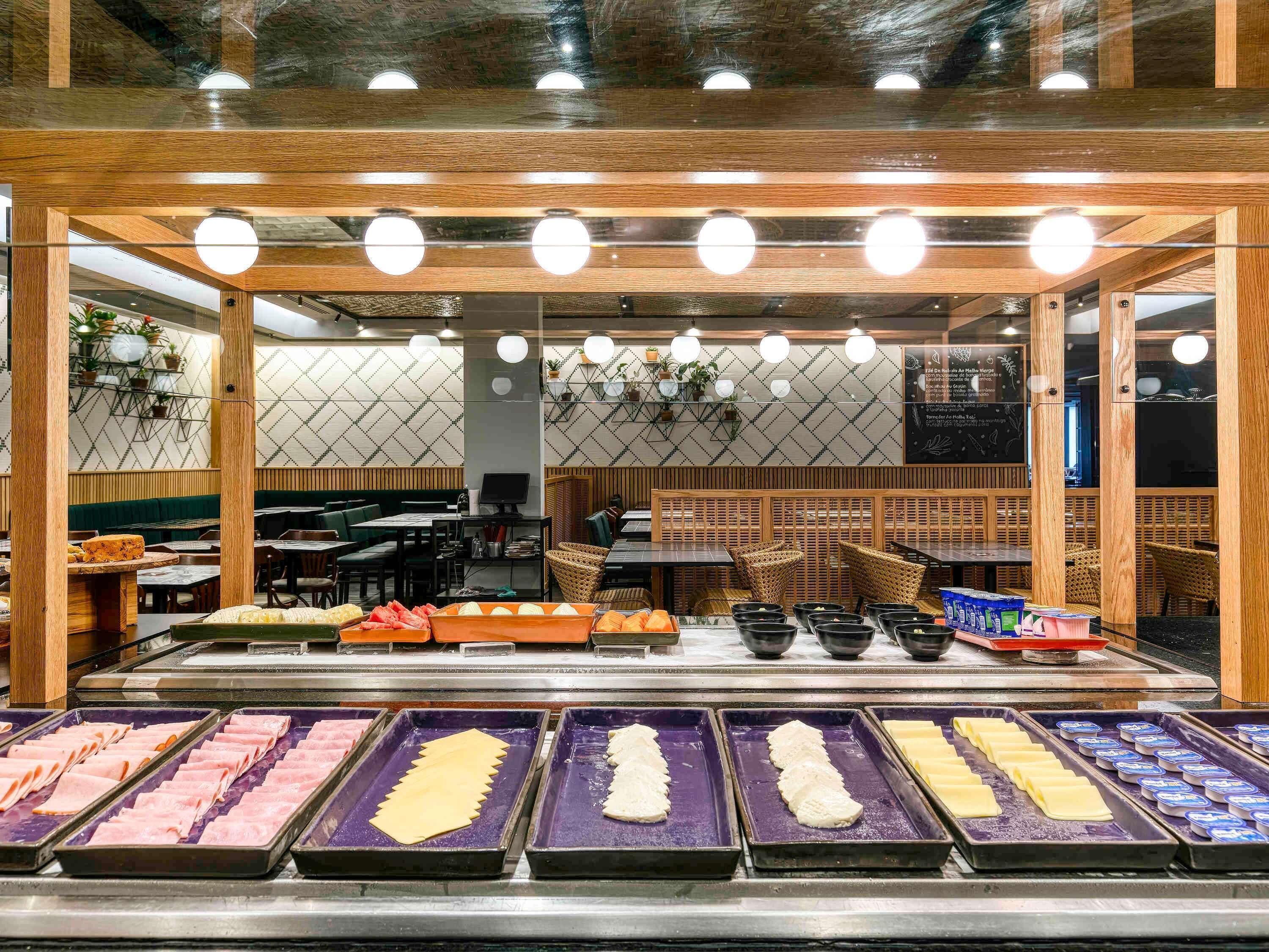 Uma área de buffet com diversos alimentos dispostos em bandejas.