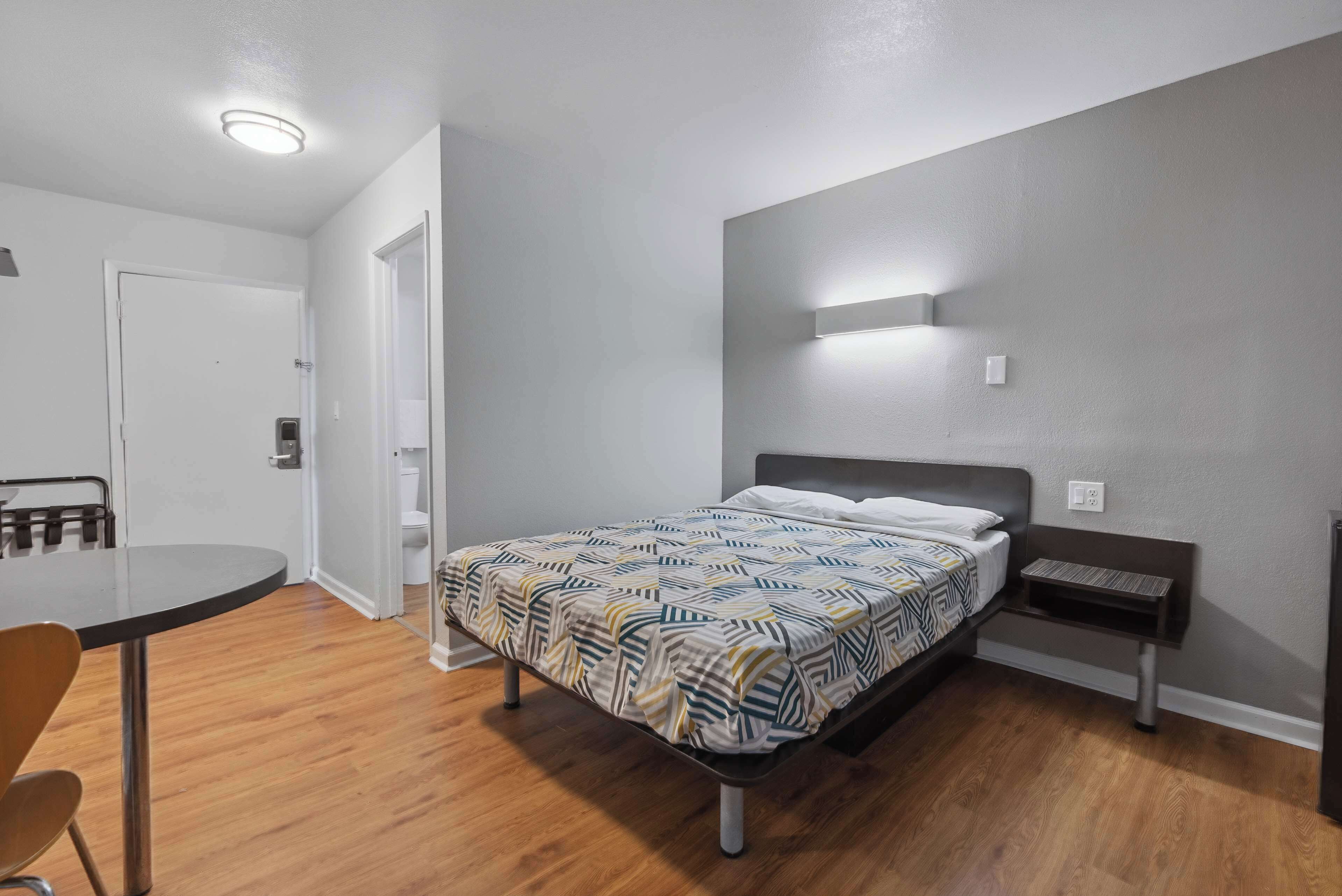 A modern bedroom with a bed, bedside table, and a small desk.