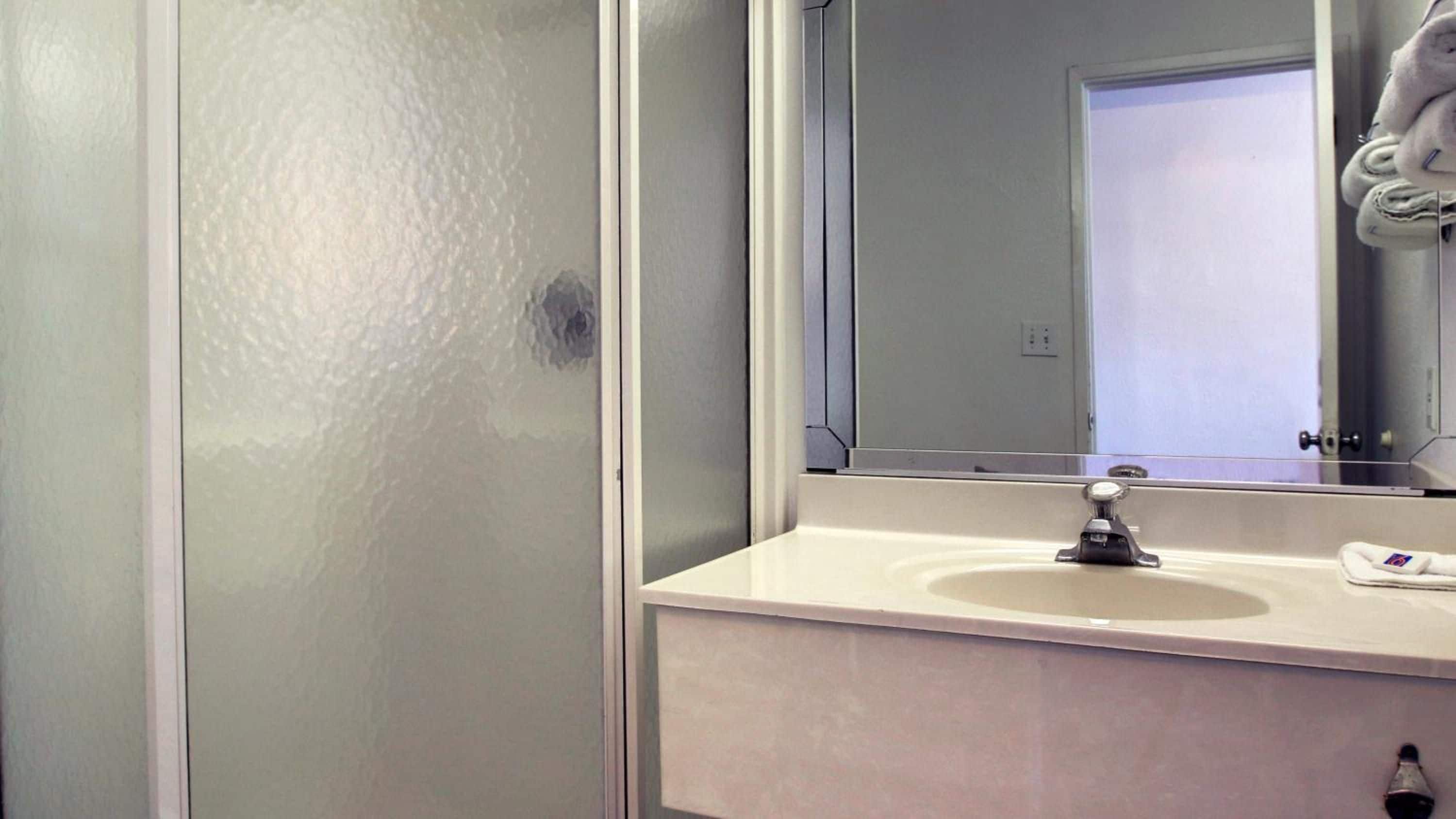 A bathroom with a white sink, a mirror, and a towel hanging on a rack.