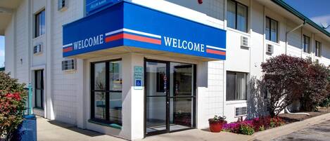 A motel with a 'WELCOME' sign, a '100 FINE' parking sign, and a 'RESERVED PARKING' sign.