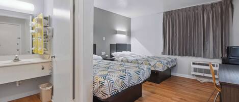 Un dormitorio moderno con dos camas, una mesita de noche, un espejo, un escritorio pequeño y una silla.