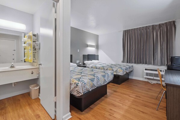 Un dormitorio moderno con dos camas, una mesita de noche, un espejo, un escritorio pequeño y una silla.