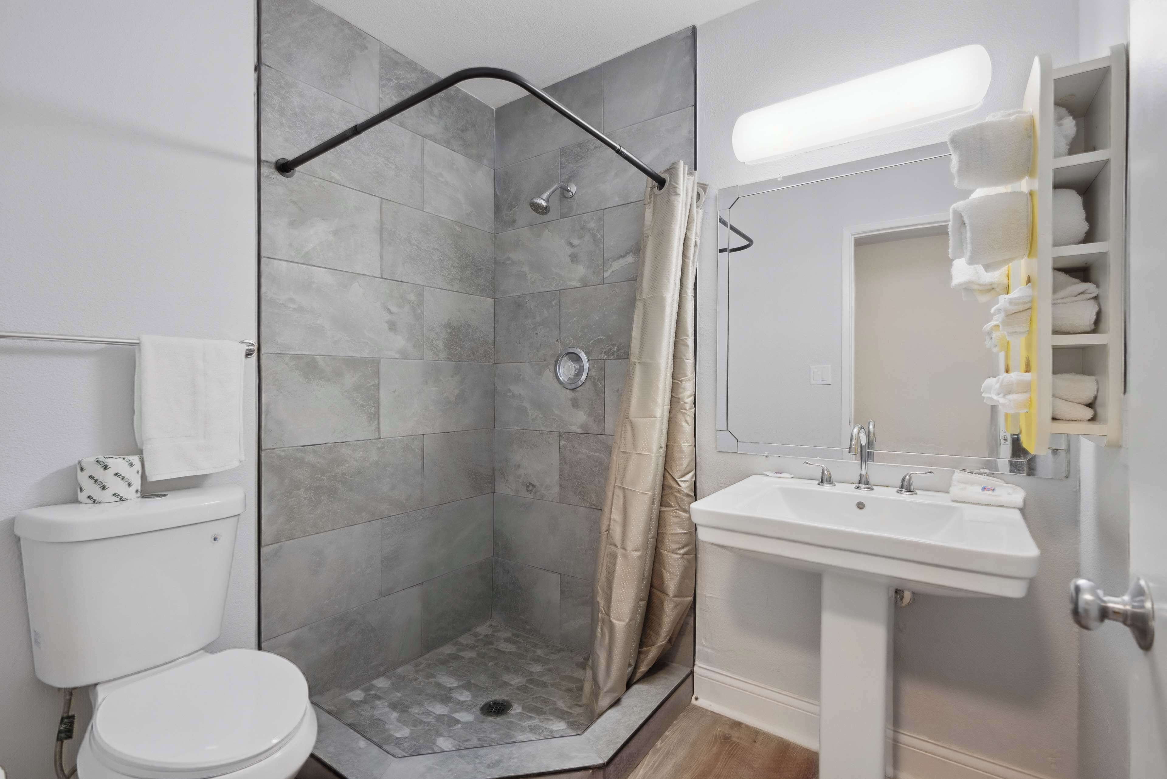 A bathroom with a shower, toilet, sink, and towel rack.